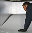 A contractor installing TerraBlock floor insulation in a Maple Ridge crawl space