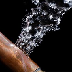 A bursting copper pipe in Richmond, with water gushing out.